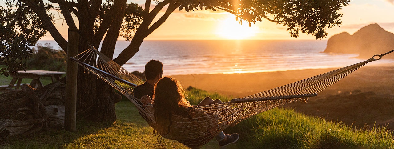 Couple in a hammock watching the sunset over Bethells Beach