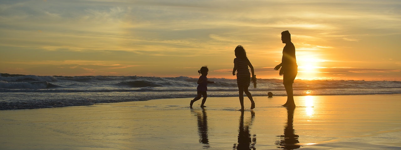A family standing on a beach at sunset