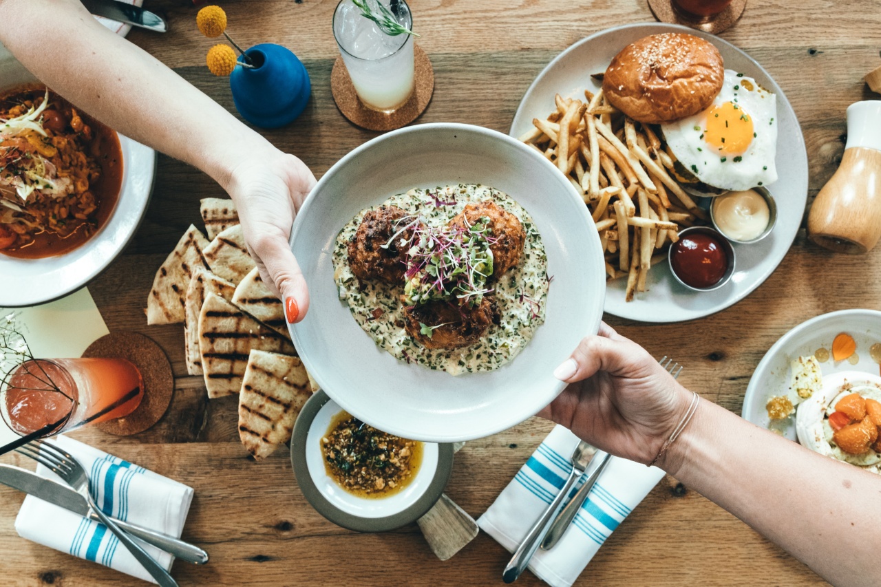 A table full of food and someone passing a plate to someone else