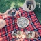a charcuterie board, pizza and bottle on a red picnic blanket