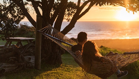 Couple in a hammock watching the sunset over Bethells Beach