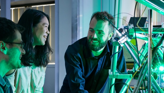 3 people playing with a robotic arm